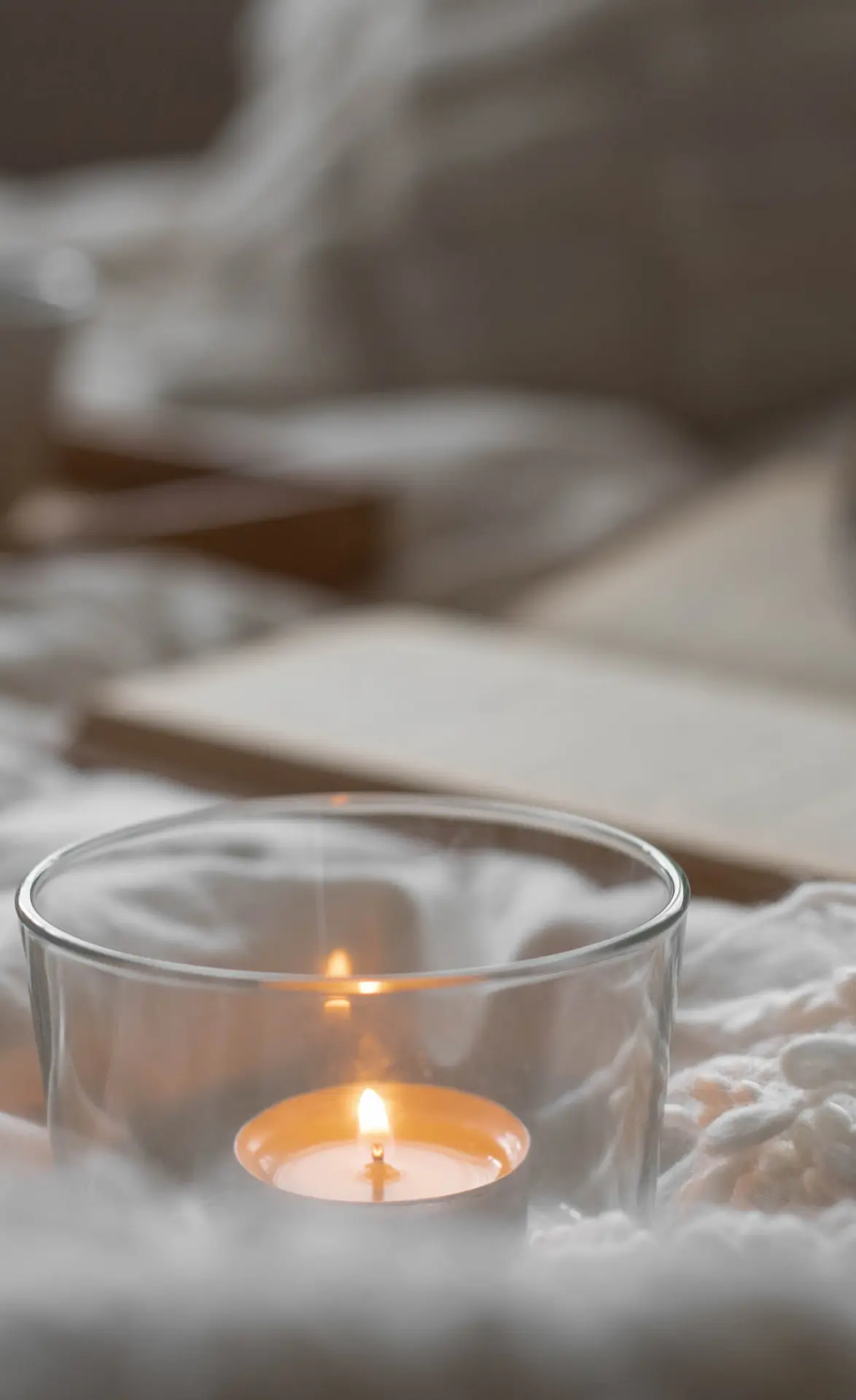A single tealight candle burning in a glass holder